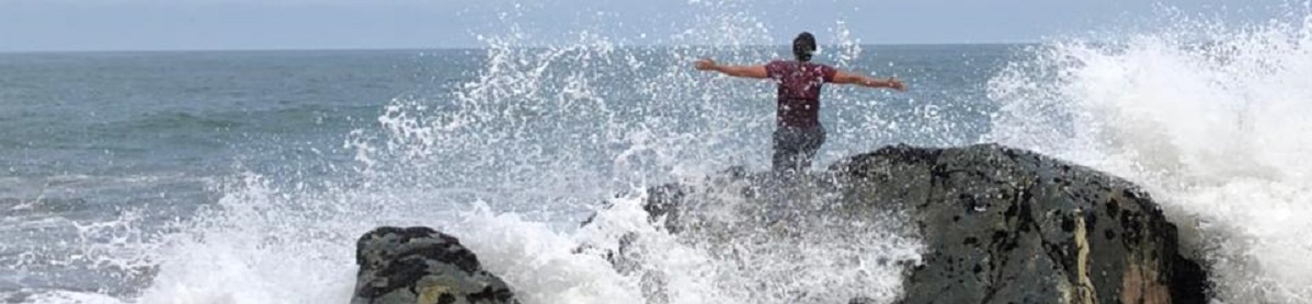 Ocean background with Chase Kimball on rock with ocean wave spray behind him